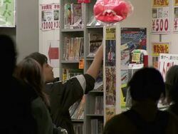 MS Shot of manga comic shop in Tokyo with pedestrians and traffic passing in front of it at night / Tokyo, Japan Stock Footage