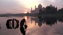 A mother collects water close to her children in the River Yamuna near the Taj Mahal in Agra, India. Stock Footage