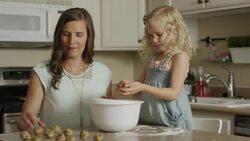 Medium panning shot of mother and daughter rolling cookie dough / Orem, Utah, United States Stock Footage