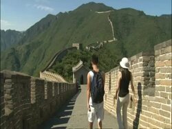 View along Great Wall of China, two tourists walk away from camera, Mutianyu, China Stock Footage