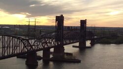 Aerial floating over railroad bridge with sun setting in the distance Stock Footage