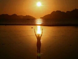 WS, silhouette woman standing in shallow waters raising and lowering arms at sunset with tropical island background / Corong Corong Beach, Bacuit Archipelago, El Nido, Palawan, Philippines Stock Footage