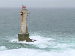 MS AERIAL DS Shot of lighthouse and waves crashing on rocks / Brittany, France Stock Footage