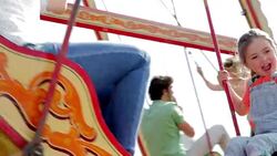 Mother and daughter riding swing at amusement park Stock Footage