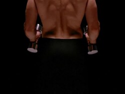 Medium shot tilt up rear view of muscular man exercising with dumbbells / London Stock Footage