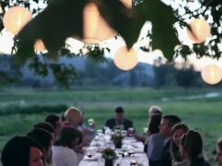 TD MS Friends and family dining outside in field under tree with lanterns at sunset/Washington, USA Stock Footage