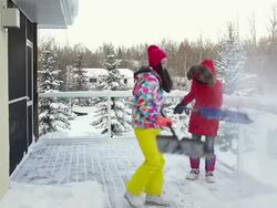 Mother and daughter shoveling snow off house deck Stock Footage