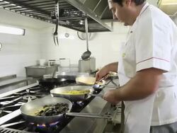 Chef pours olive oil into pans containing pasta Stock Footage