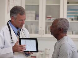 MS Doctor Looking at Records on Tablet Computer, Talking to Senior Patient in Medical Office / Richmond, Virginia, USA Stock Footage