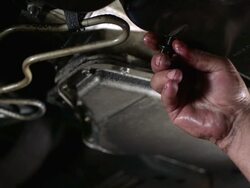 CU SLO MO Mechanics turning screw and draining oil from oil pan / Bergenfield, , New Jersey, USA  Stock Footage