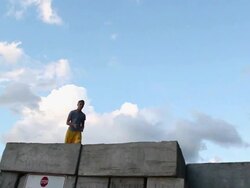 A young man jumping off a wall during sunset at the beach. - Model Released - HD Stock Footage
