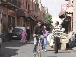 MS Shot of people walking on street with houses and car around / Marrakesh, Morocco Stock Footage