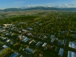 Aerial wide shot forward POV passing over Main Street in Bozeman, MT then looking south toward distant mountains Stock Footage