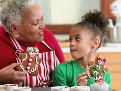 MS Grandmother and Granddaughter Eating Gingerbread Men Cookies in Kitchen / Richmond, Virginia, USA Stock Footage
