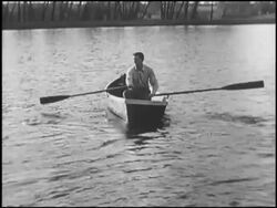 Man rowing across lake with uneven oars Stock Footage