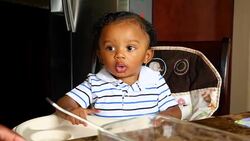 MS Infant boy sitting in highchair during breakfast Stock Footage