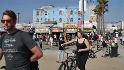 Venice Beach visitors walk near the Venice Beach mural by Rip Cronk titled, Venice Reconstituted, which was painted in 1989 at Windward Avenue. Stock Footage