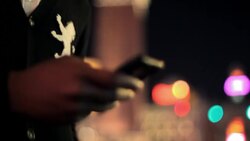 A young Black man wearing a crested jacket sends a text message. Stock Footage