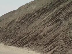 Textured, dark rock streaks downwards to the valley floor of the Atlas mountains. Stock Footage