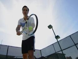 LA WS of a man bouncing and serving a tennis ball with the sun behind him. Stock Footage