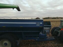 The auger from a combine finishes dumping corn into a wagon and it pulls away. Stock Footage