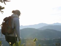 Woman hiker pauses on ridge above distant hills Stock Footage