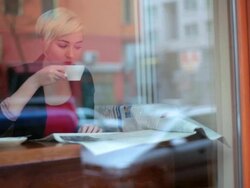 MS Shot of Woman reading newspaper and drinking coffee by window in cafe / Berlin, Germany  Stock Footage