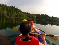 Girls paddling Kayak across a lake with pet dog Stock Footage
