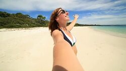 Cheerful young woman takes a selfie portrait on the beach Stock Footage