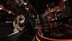 Hollywood couple recline in limousine, wave to fans, and clink champagne glasses at awards show Stock Footage