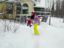 Mother and daughter shoveling snow off house deck and walkway Stock Footage