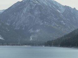 WS TD View of Lake Wallowa glistens on sunny winter day with snowy mountains rising steeply, From Oregon's "Little Switzerland" / Joseph, Oregon, United States Stock Footage