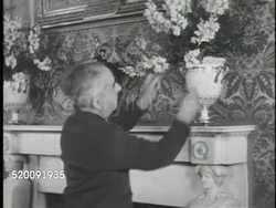 1948: WASHINGTON, D.C.: THE WHITE HOUSE: VS Red Room, male floral staffer arranging mantle vase flowers. ART COLLECTION: MS Grover Cleveland painting by Eastman Johnson, CU Bottom frame information, VS Theodore Roosevelt by John Singer Sargent. Instructional Video