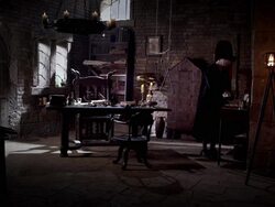 Nostradamus walks to a small table and retrieves an item then returns to his desk. Stock Footage