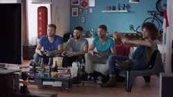 Guys sitting on couch playing video games and cheering Stock Footage