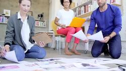 Creative business people reviewing proofs on office floor Stock Footage