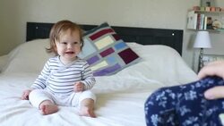 A baby girl laughing and having fun on a bed inside a home. Stock Footage