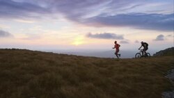 TS runner and mountain biker on the plateau at sunset Stock Footage