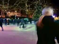 MS T/L Shot of Natural History Museum Ice Skating Rink, skaters passing and trees with Xmas lights / London, Greater London, United Kingdom Stock Footage