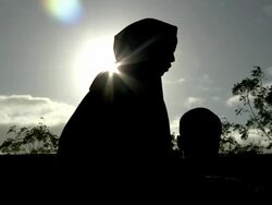 Refugee woman and child silhouetted by sunlight Stock Footage