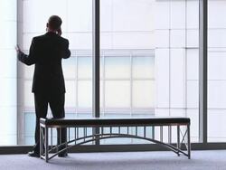  WS Businessman rocking on his feet talking on cell phone, then sitting down on bench / Seattle, Washington, United States Stock Footage