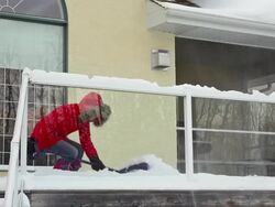 Mother and daughter shoveling snow off house deck Stock Footage