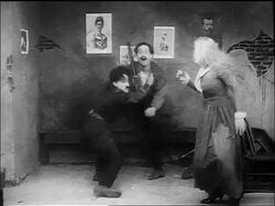 B/W 1917 policeman Charlie Chaplin fighting junkie, hugging woman + kicking second man Stock Footage