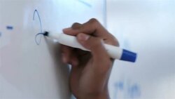 Hip young businessman's hand writes on conference-room white-board Stock Footage