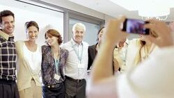 Businesswoman with camera phone photographing co-workers in office Stock Footage