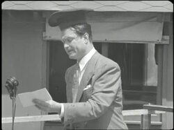 Comedian Red Skelton reads a poem while wearing an upside-down hat in a USO show. News Clip