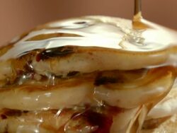 ECU stack of blueberry pancakes as maple syrup is poured over the top and drips along the edges of layered pancakes Stock Footage