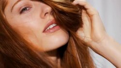 Woman pushes hand through her red hair to cover parts of her face creating volume, movement and a tousled look Stock Footage