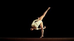 SLO MO Female gymnast performing a flip on balance beam Stock Footage