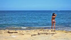 Beautiful attractive young black-haired girl standing by the sea Stock Footage